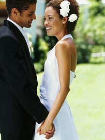 side profile of a newlywed couple holding hands on a lawn